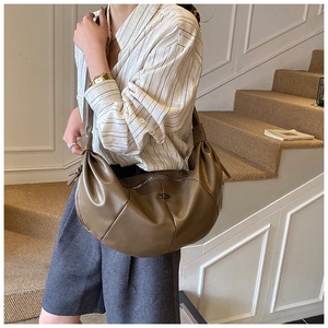 Detail of olive green ruched hobo bag with knotted shoulder strap and textured leather