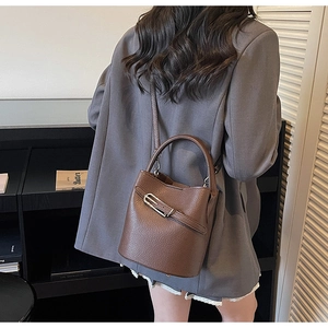 Detailed view of dark brown lychee texture leather bucket bag with metal buckle detail
