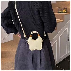 Mini sac à main chic beige en forme d'étoile avec perles en bois porté par un modèle