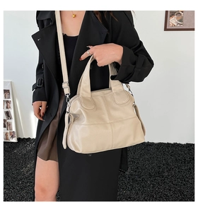 Close-up of beige leather tote bag with lychee texture and adjustable strap on a model