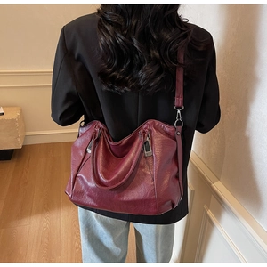 Detailed view of large burgundy leather tote bag styled with black blazer and casual jeans