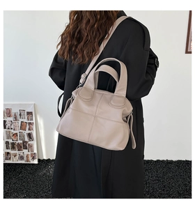 Detail view of the side profile and texture of the large apricot leather tote bag on shoulder