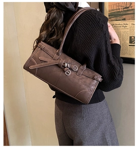 Detail of dark brown retro shoulder bag with metallic buckle on textured sweater