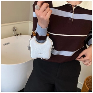 Détail du sac argenté en forme de papillon avec poignée en perles de bois marron