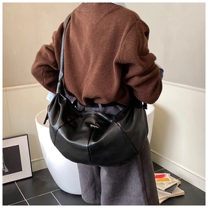 Detail of a vintage black hobo bag with pleated leather and silver oval metal buckle
