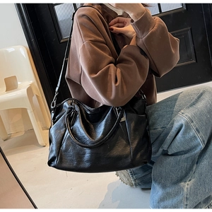 Macro view of the large capacity black handbag showing the glossy wrinkled leather texture