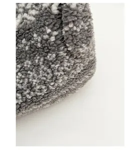 Vue macro détaillée montrant la texture bouclée en laine d'agneau grise et blanche du cabas
