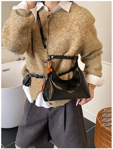 Détail du sac sous l'aisselle noir brillant avec perles orange et logo de la marque