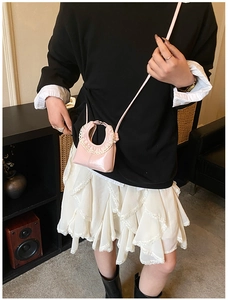 Detail of pink patent leather cloud bag with white lace trim and embossed logo