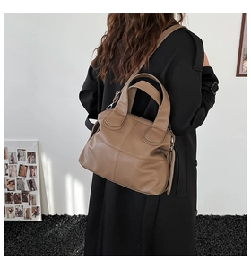 Detail view of earth-tone leather tote bag featuring fine stitching and dual handles