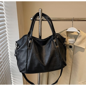 Close-up of black leather tote bag showing soft lychee texture and silver hardware details