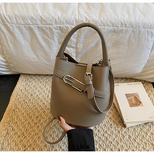 Detail view of brown pebble grain leather bucket bag with silver metal latch closure