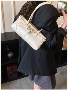 Model wearing a minimalist cream PU leather shoulder bag with sleek silver buckle detail