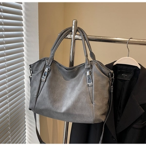 Detail view of grey faux leather tote bag showing soft texture and silver hardware accents