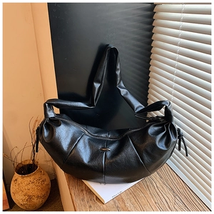 Detail of black crescent hobo bag with pleated leather texture and metallic clasp