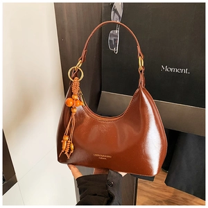 Détail du sac hobo marron en similicuir avec pompon en perles de bois et boucles dorées