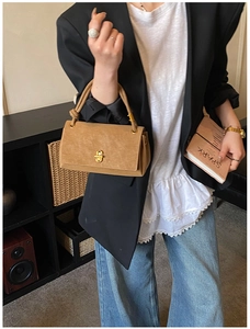 Close-up of camel suede rectangular handbag with gold twist lock on a vintage background