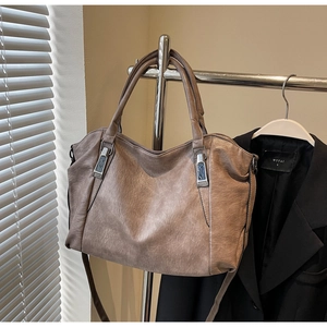 Close-up of brown faux leather tote bag with silver hardware on a professional garment hanger