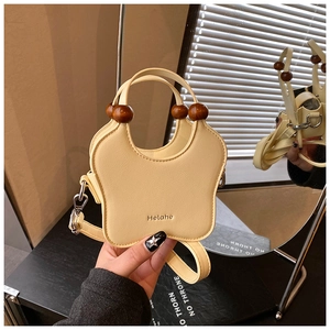 Détail du sac à main beige en forme de papillon avec une poignée en perles de bois