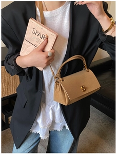Detail of camel suede handbag featuring gold twist lock and adjustable shoulder strap