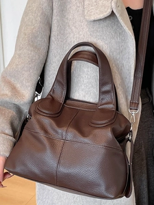 Deep brown pebble leather handbag with detachable strap worn on grey woolen coat