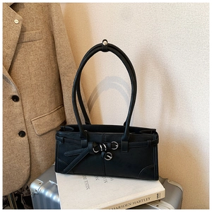 Close-up of black leather handbag with silver buckle detail on a silver suitcase
