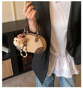Detail of vintage bowling bag with bear charm and pearl strap on model side view