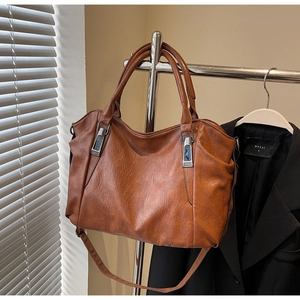 Detail view of caramel brown large tote bag with vintage texture and metal hardware accents