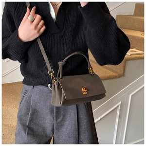 Détail d'un sac à main gris foncé mat avec fermoir doré rotatif et poignée nouée