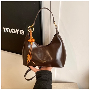 Détail d'un sac sous les bras vintage marron avec gland en bois et logo doré brillant
