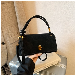Détail d'un sac à main rectangulaire en daim noir avec fermoir doré et poignée nouée