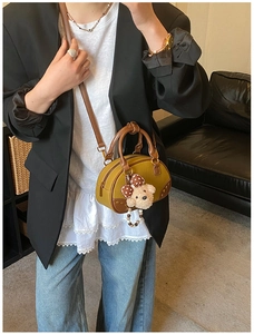 Detail of a vintage yellow mini Boston bag with teddy bear charm and pearl chain decoration