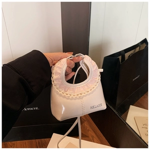 Close-up of a white leather cloud bag with pink plaid lace handle and gold logo
