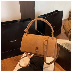 Détail du sac bandoulière en daim camel avec fermoir doré et boucles latérales décoratives