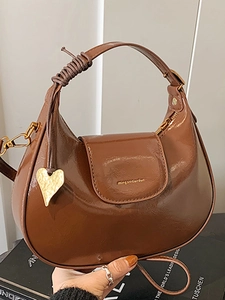 Brown patent leather crescent bag with woven handle and gold heart charm detail