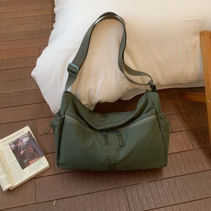 Detail of dark green waterproof nylon crossbody bag with dual front zipper pockets