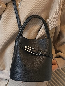 Vintage black lychee leather bucket bag with silver buckle worn by a woman