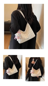 Détail du sac hobo beige à carreaux avec une peluche mignonne portée par un mannequin