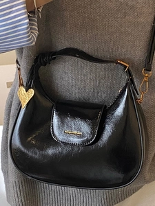 Minimalist black oil wax leather crescent hobo bag with gold heart pendant and logo