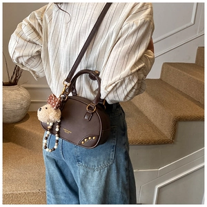 Detail view of coffee bowling bag with plush bear charm and beaded chain accessory