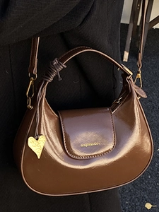 Polished brown half-moon hobo bag with gold heart charm and glossy finish