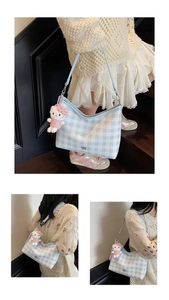 Détail du sac hobo à carreaux bleu clair avec un charm de poupée en peluche rose
