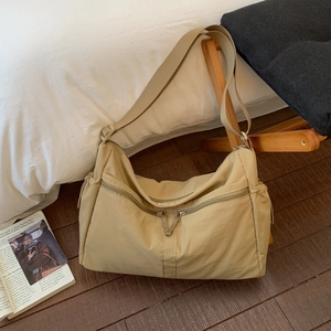 Detail of light khaki nylon tote bag featuring dual front zippers and wide strap