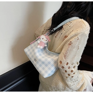 Détail d'un sac sous les aisselles à carreaux bleus avec une petite peluche décorative