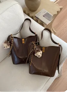 Detailed view of deep brown vintage tote bags with plush bear charm and metallic hardware