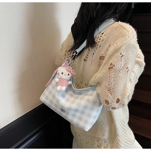 Détail du sac hobo à carreaux bleu et blanc avec un pendentif en peluche sur la bandoulière