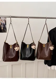 Three retro bucket tote bags in dark brown, black, and tan with bear charms