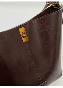 Detail shot of vintage dark brown bucket bag featuring oil-finish leather and bronze buckle
