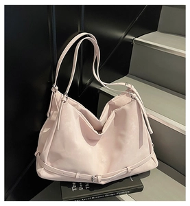 Detail of light pink hobo tote bag featuring adjustable straps and silver metal buckles