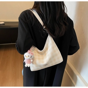 Détail du sac hobo à carreaux crème et beige avec bandoulière blanche et charme en peluche